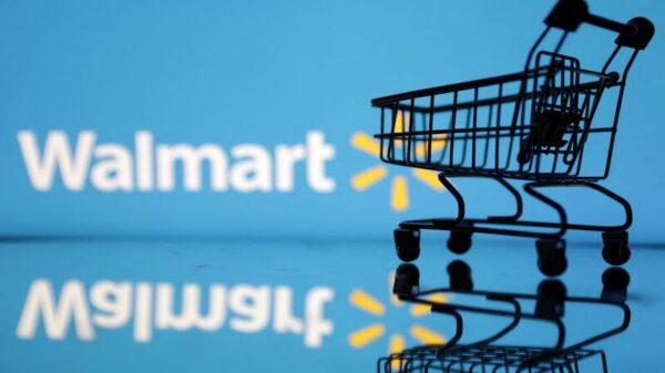 Shopping trolley is seen in front of Walmart logo in this illustration