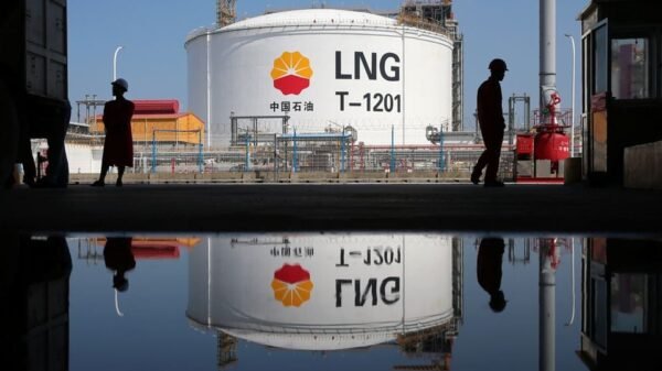 A liquified natural gas(LNG) storage tank and workers are reflected in a puddle at PetroChina's receiving terminal at Rudong port in Nantong, Jiangsu province, China September 4, 2018. REUTERS/Stringer/File Photo